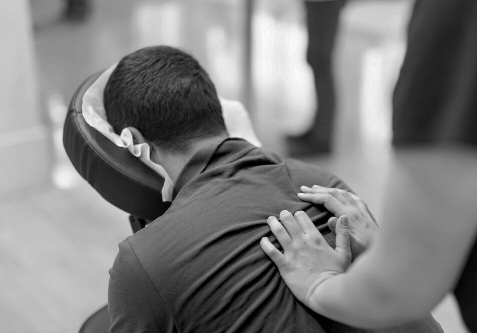 Man receiving shiatsu on a quick massage chair Man seated in a massage chair for back massage.